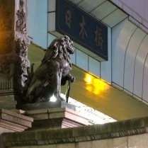 The plaque reads "Nihonbashi", the name of the bridge. Though I should clarify Nihonbashi is the bridge these statues are on, not the overpasses above. (May 2016)